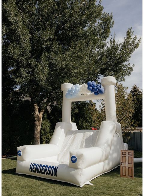 White bounce house with a slide and blue balloons