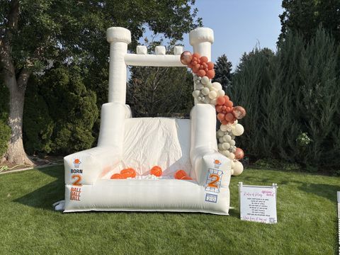 Bounce house with basketballs and an orange and white balloon garland