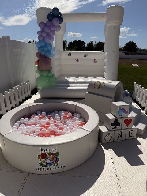 Alice in Wonderland-themed ball pit, soft play blocks, and bounce house with balloon garland