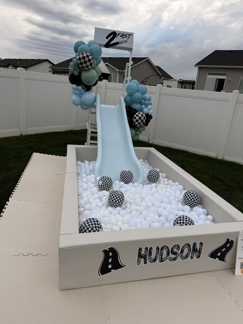 Race car-themed ball pit and slide with a checkered balloon garland