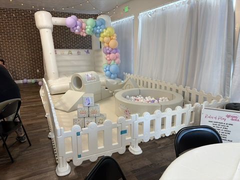 Pastel indoor soft play set and bounce house with rainbow balloon garland