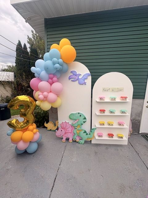 Pastel balloon arch backdrop with a dinosaur-themed display board